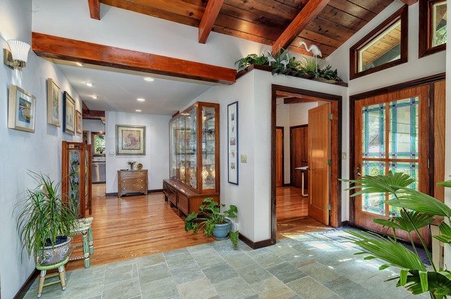 entrance with marble floor and living room with wooden floor . wooden ceiling made of beams anfd plugs