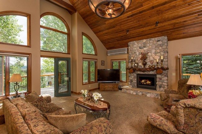 big windows living room made from stones with pile soft carpet on the floor and round wooden ceiling