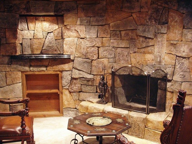 living room with rock big stone fireplace with square wooden tea table and with middle age europininan armchairs