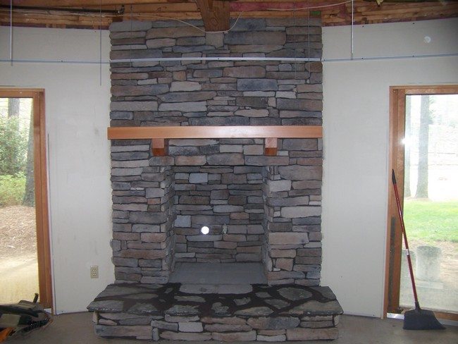 grey stone rock fireplace just finishe with wooden shelf undet it