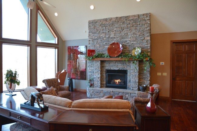 light stone rock fireplace in the living room with corner leather sofa with dark wooden floor