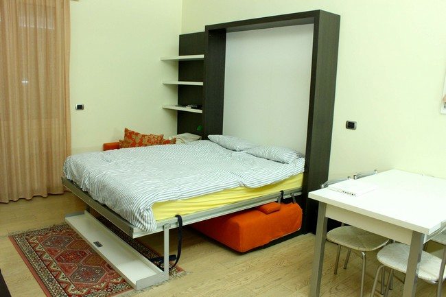 double bed vertical with orange sofa under it with eastern asian carpet on the floor