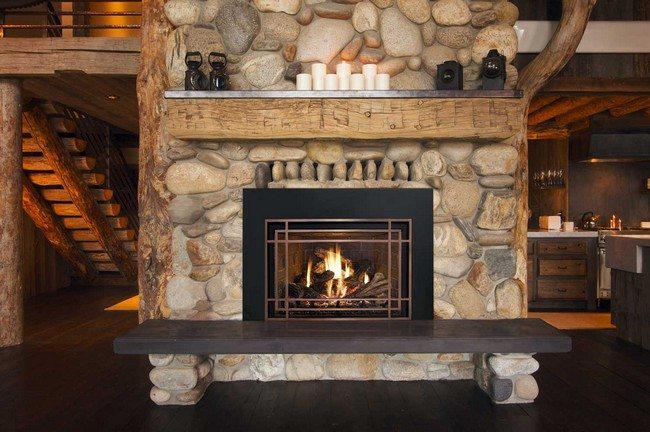 stone fireplace in the cozy house , marble bench in front of the stone . wooden ladder made from whole beam