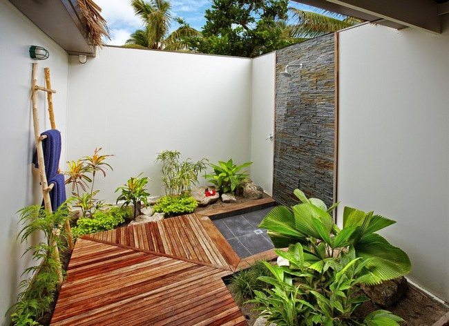 outdoor shower with wooden path to it and live green vegetables