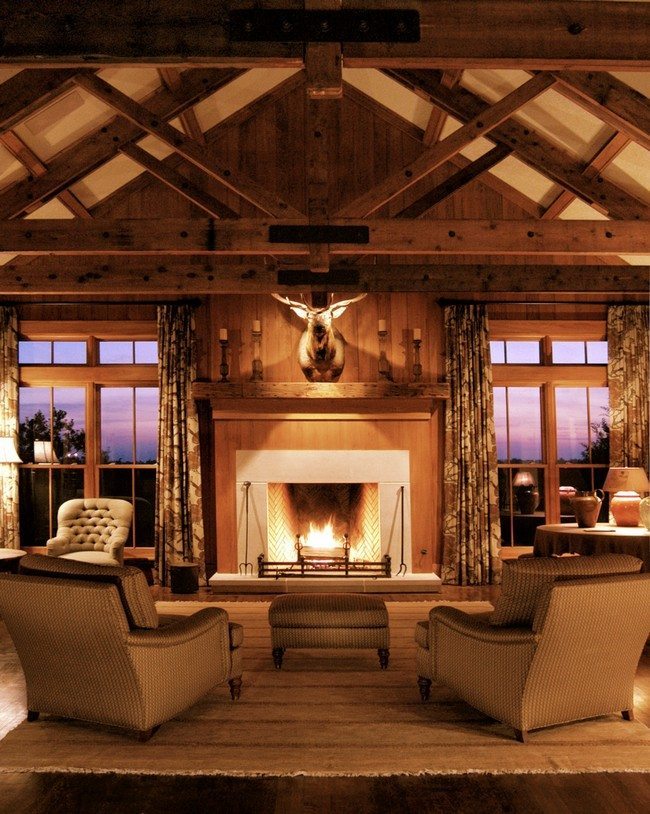 big living room. with 2 big chairs and small tea table. two big windows , a deer head above the fireplace