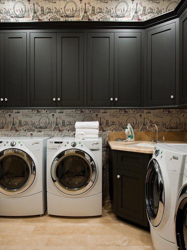 Washing machines and dryer aligned against the wall and upper-located cabinets against creative wallpaper