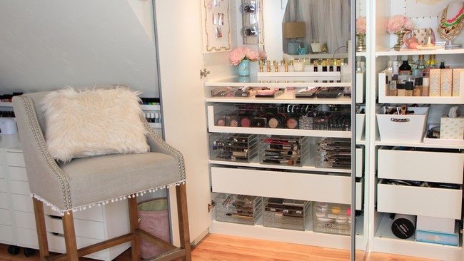 mirrored makeup storage with different sheleves full of cosmetics and small chair