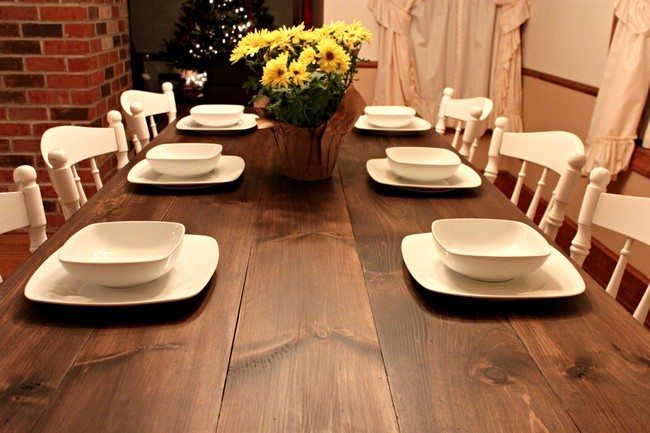 wooden table with white chairs and white dishes on it