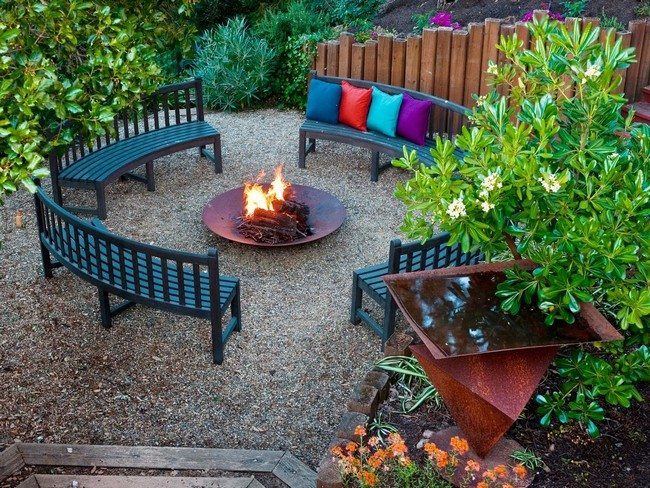 Place for fire with benches around fireplace covred with multicolor cushions