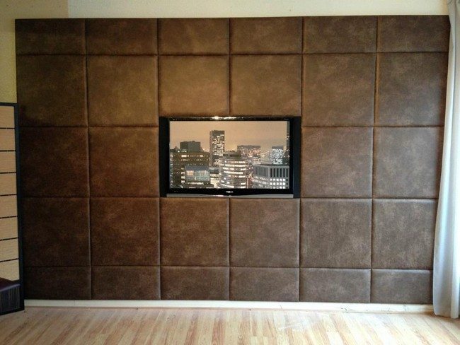 Television screen mounted on brown tufted wall panel