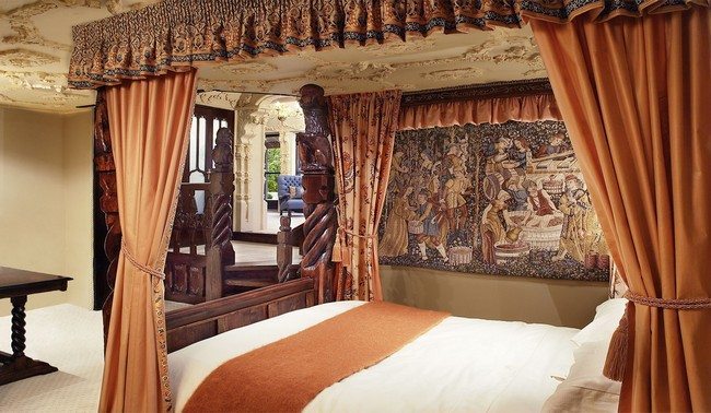 Heavy orange drapes covering a four-poster bed