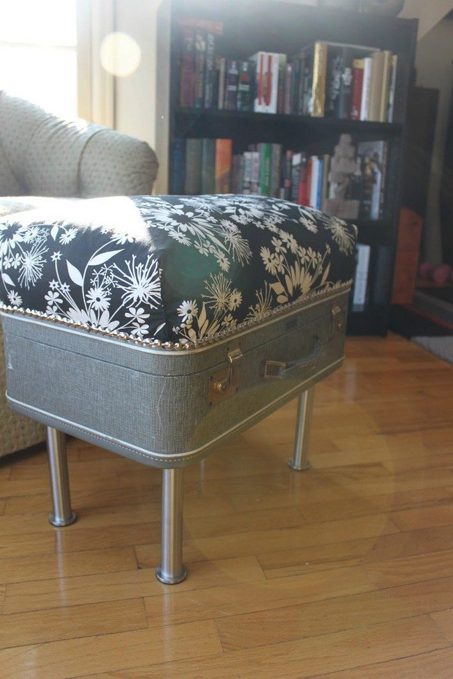 Old suitcase converted into small, upholstered coffee table