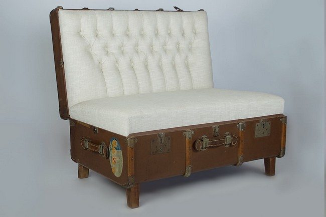 Old suitcase upholstered into a chair with four wooden stands