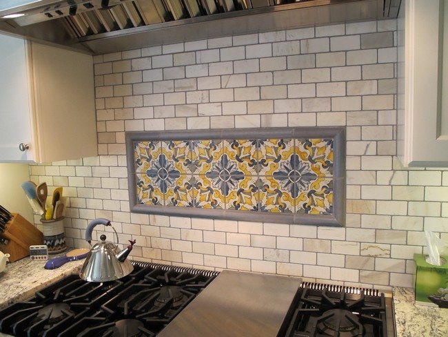 Painted subway tile backsplash with artistic tile detail in the middle
