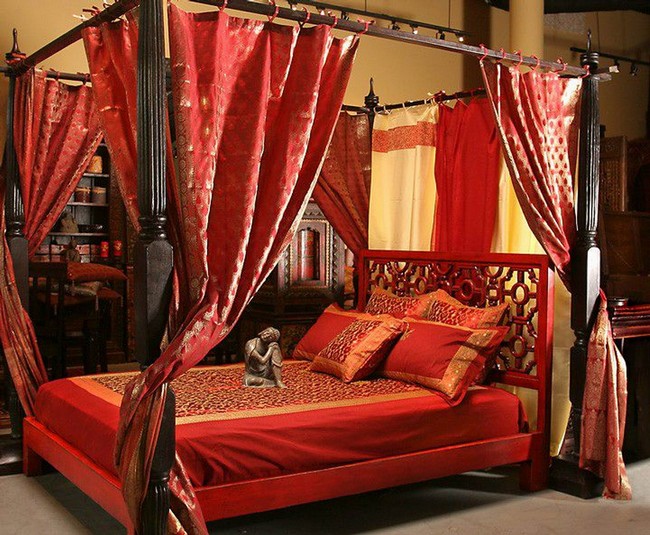 Four-poster bed with red bedding and drapes