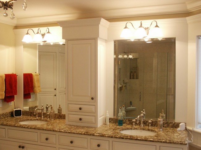 White lighting above twin mirrors separated by a cabinet in the middle