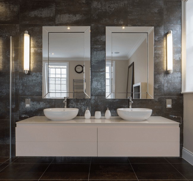 Twin mirrors placed against grey mosaic wall