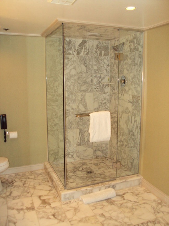 Shower area with marble tiles and glass wall