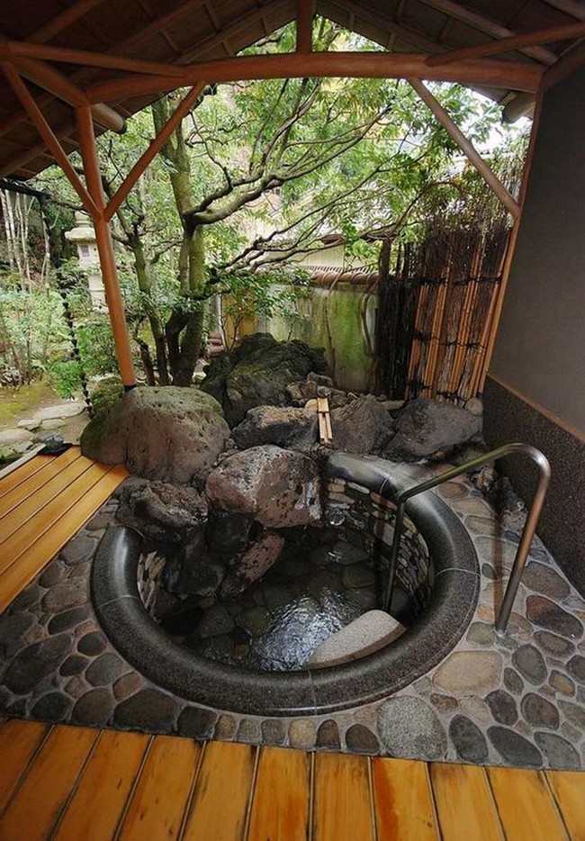Outdoor bathtub surrounded by a small rock gardens