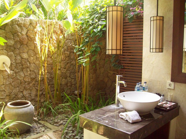  Heavy stone wall surrounding outdoor bathroom with a few plants