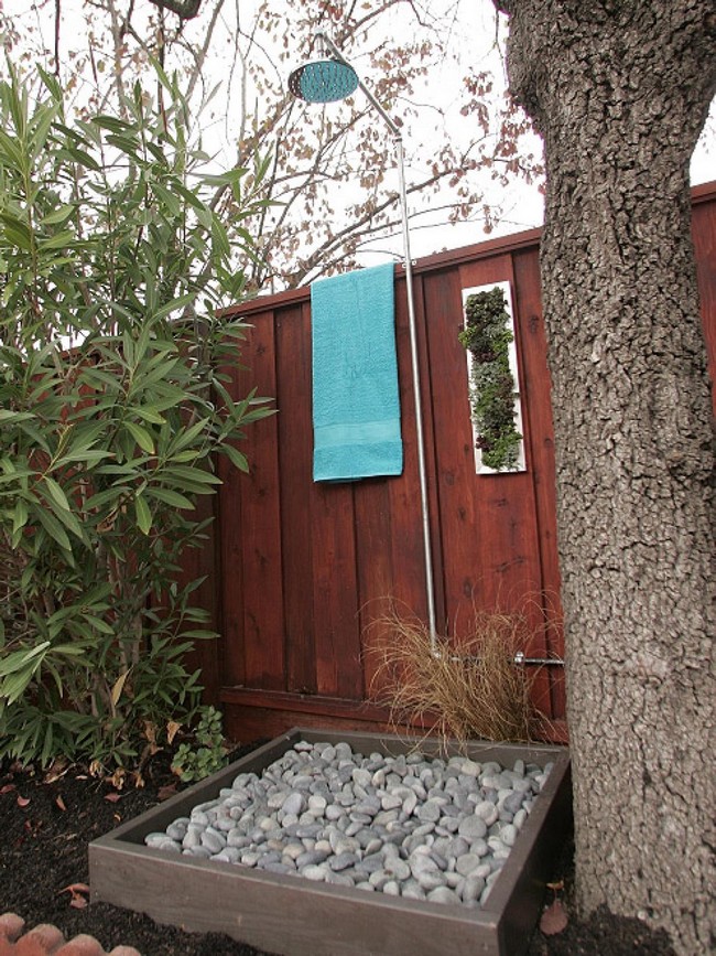 Small, outdoor shower area with floor made from pebbles