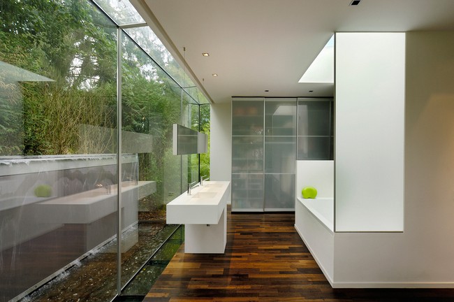Outdoor bathroom with white color scheme and extensive glass wall that lets in sunlight