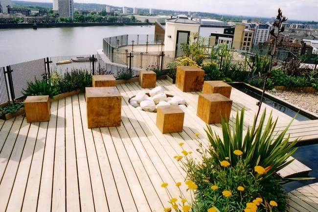 Creative use of wooden blocks for seats in a contemporary terrace adjacent to a water body