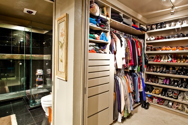 Elegant walk-in-closet with a large glass door and floor-to-ceiling shoe rack
