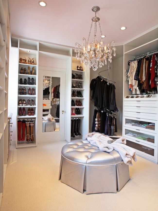 Extravagant contemporary women’s closet with a crystal chandelier hanging over a silvery pouffe