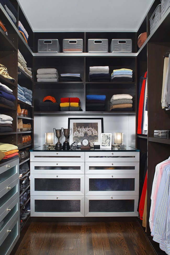 Men’s closet with drawers that have frosted doors, paired with a dark hardwood floor